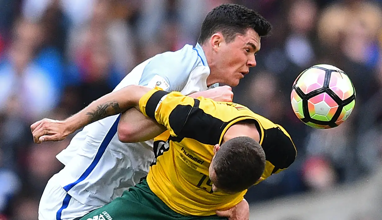 Penyerang Lithuania, Nerijus Valskis, duel udara dengan bek Inggris, Michael Keane. Inggris mendominasi pertandingan dengan penguasaan bola hingga 68 persen sementara Lithuania hanya 32 persen. (AFP/Glyn Kirk)