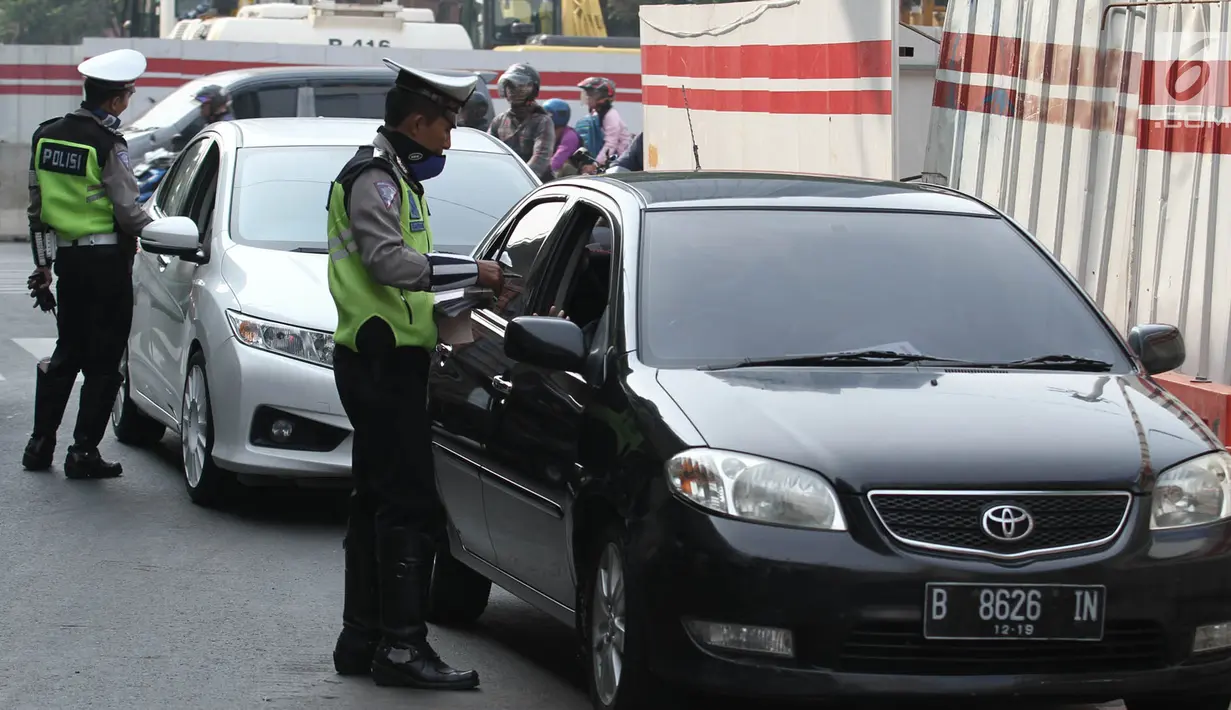 Polisi memberikan surat tilang kepada pengemudi mobil berpelat nomor genap di Jalan MT Haryono, Jakarta, Rabu (1/8). Polisi hari ini mulai memberlakukan sanksi tilang kepada pelanggar aturan di kawasan perluasan ganjil genap (Merdeka.com/Iqbal S. Nugroho)