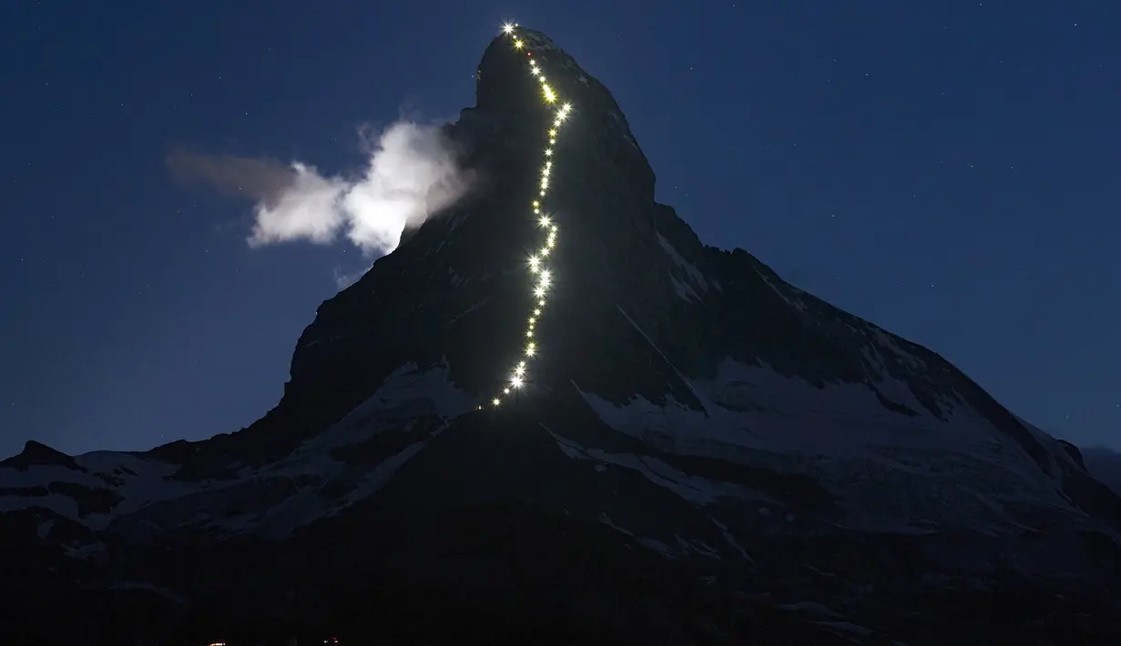 Deretan cahaya memanjang, terlihat di punggung gunung Matterhorn, Zermatt, Swiss, Senin (13/7/2015). Lampu tersebut dipasang merayakan keberhasilan Briton Edward Whymper, menaklukan puncak gunung Matterhorn pada 14 Juli 1865. (REUTERS/Denis Balibouse)