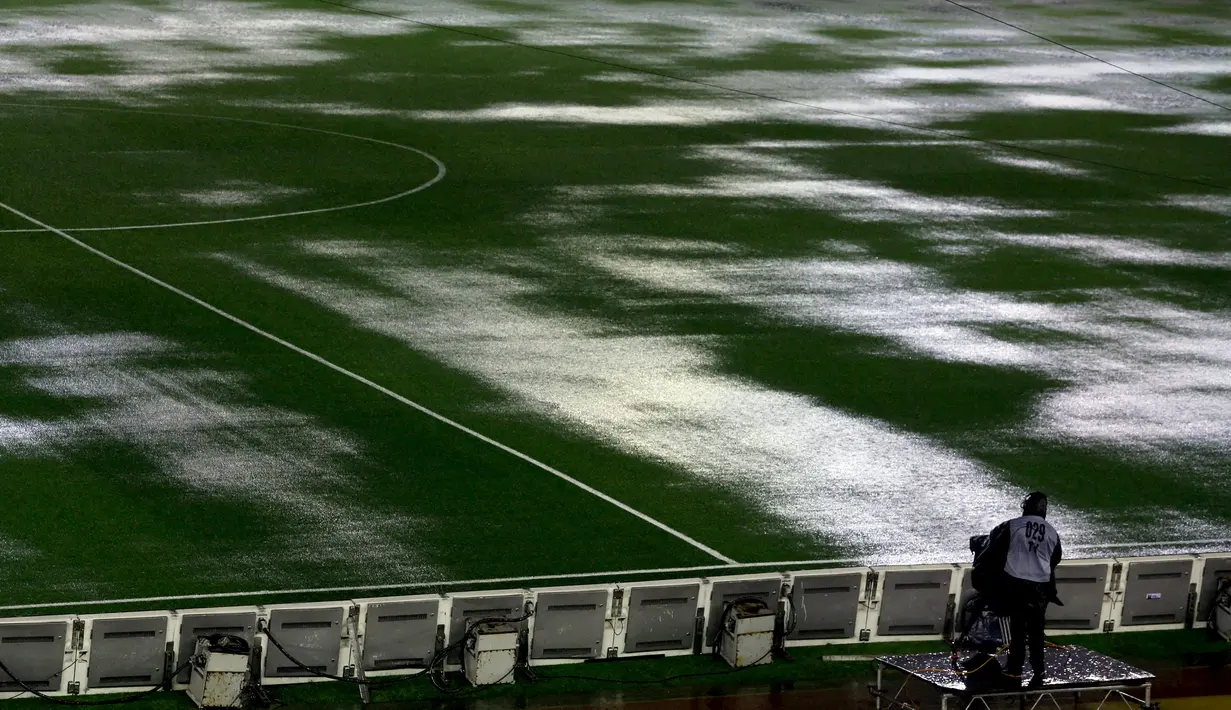 Seorang kamerawan berdiri di pinggir lapangan Stadion Monumental, Buenos Aires, Argentina, yang banjir karena guyuran hujan deras sebelum laga Kualifikasi Piala Dunia 2018 antara Argentina melawan Brasil. Jumat (13/11/2015) WIB. (Reuters/Marcos Brindicci)