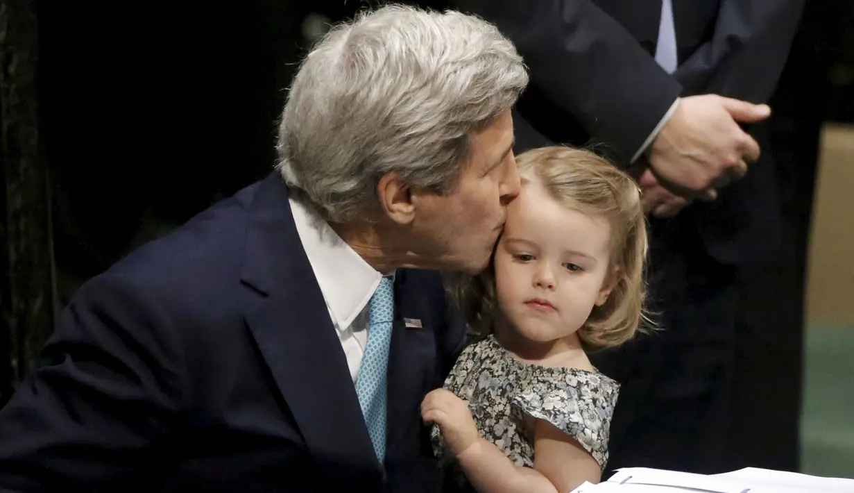 Menteri Luar Negeri AS John Kerry mencium cucunya Isabelle Dobbs-Higginson saat menandatangani surat Perjanjian Paris tentang perubahan iklim di Markas Besar PBB, Manhattan, New York, AS (22/4). (REUTERS / Carlo Allegri)