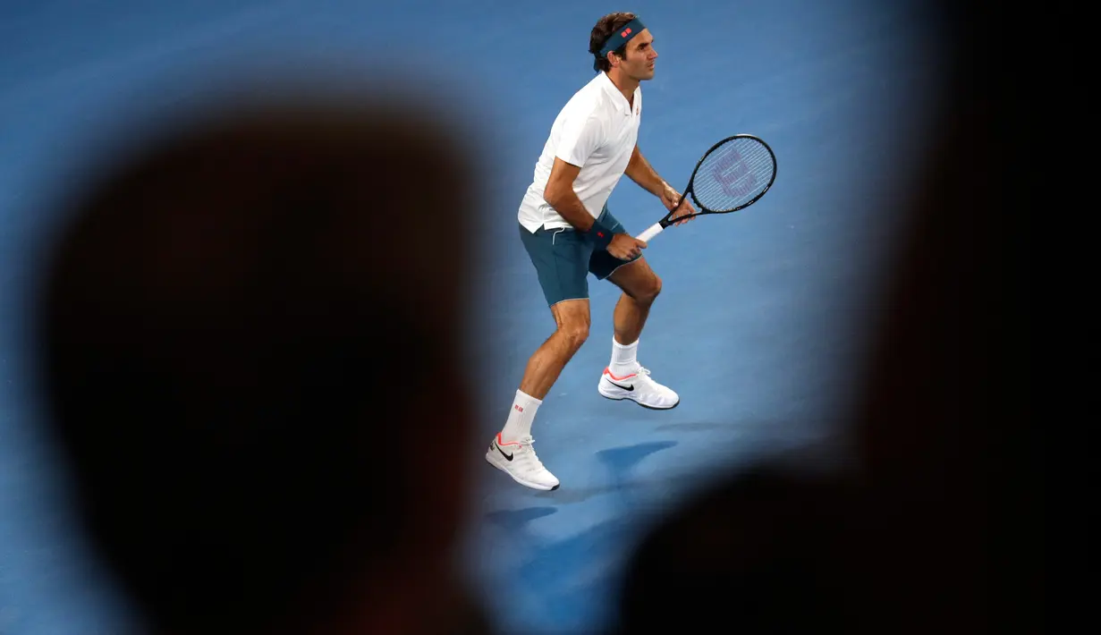 Petenis Swiss, Roger Federer bersiap menerima servis dari petenis AS, Taylor Fritz dalam babak 32 besar Australia Terbuka di Melbourne, Jumat (18/1). Federer melaju mulus ke babak 16 besar setelah menang tiga set langsung 6-2 7-5 6-2. (AP/Kin Cheung)