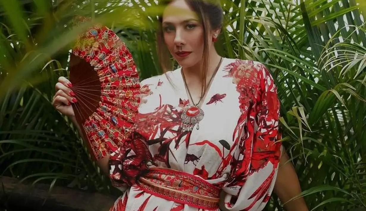 Penampilannya dilengkapi aksesori kalung dan ikat pinggang berwarna merah senada. [@theomono/@wulanguritno].