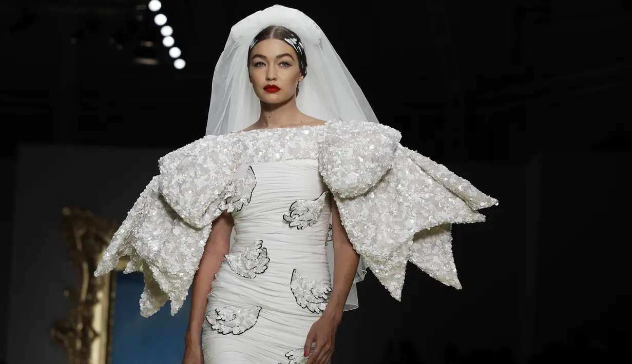 Model Gigi Hadid memakai koleksi Moschino Spring-Summer 2020 selama pekan mode di Milan, Italia (19/9/2019). Gigi tampil anggun dengan sentuhan apik pada balutan gaun pengantin berwarna putih untuk showcase unik yang terinspirasi oleh Alice In Wonderland. (AP Photo/Luca Bruno)
