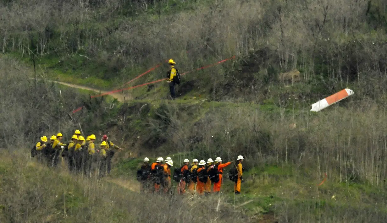 Sejumlah petugas berusaha mengevakuasi korban jatuhnya helikopter di Calabasas, California, Minggu (26/1/2020). Legenda NBA, Kobe Bryant, menjadi salah satu korban tewas pada kecelekaan helikopter berjenis Sikorsky S-76B itu. (AP/Mark J. Terrill)