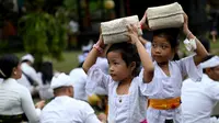 Anak-anak umat Hindu mengikuti perayaan Hari Raya Galungan di sebuah pura di Bali, Rabu (4/1/2023). Hari Galungan diperingati dengan serangkaian upacara hingga berakhir di Hari Kuningan. (SONNY TUMBELAKA / AFP)
