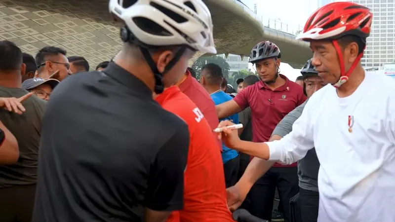 Presiden Joko Widodo atau Jokowi saat menandatangani baju salah satu warga di CFD Jakarta.