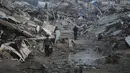 Menurut Direktur Operasi Komite Internasional Palang Merah (ICRC), Yasmine Praz Dessimoz, pembukaan kembali perlintasan di perbatasan Rafah sangat penting untuk menyediakan bantuan kemanusiaan dalam jumlah yang cukup ke Jalur Gaza. Tampak dalam foto, warga Palestina berjalan di tengah bangunan yang hancur akibat serangan udara dan darat Israel di Kota Gaza, Selasa 6 Januari 2026. (AP Photo/Jehad Alshrafi)
