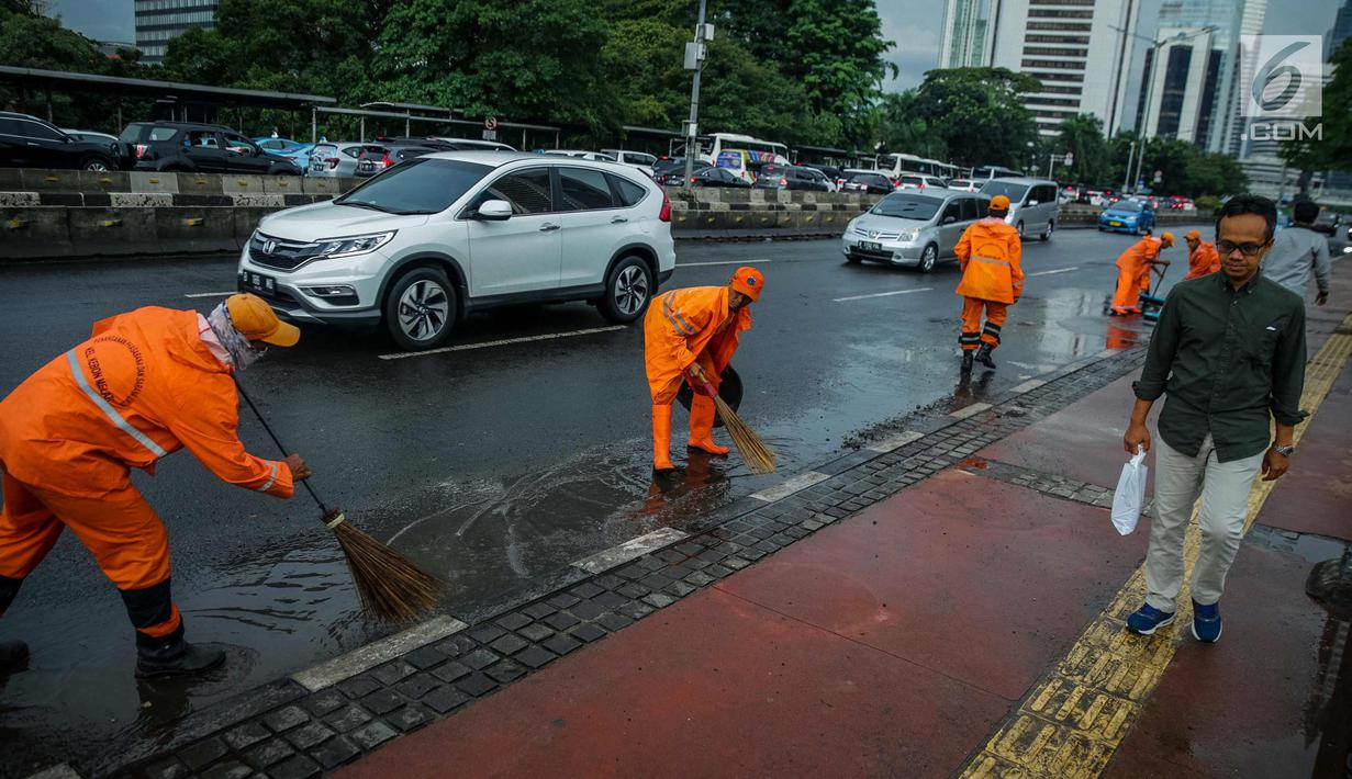 Petugas Dinas Kebersihan membersihkan genangan air usai hujan di kawasan jalan Sudirman, Jakarta, Rabu (22/11). Buruknya sistem drainase membuat petugas membersihkan genangan setiap kali hujan, meski dengan peralatan seadanya. (Liputan6.com/Faizal Fanani)