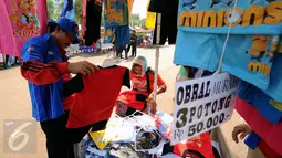 Seorang buruh memilih pakaian anak yang dijajakan di sekitar kawasan Monas, Jakarta, Selasa (1/9/2015). Ribuan buruh yang tergabung dalam berbagai elemen organisasi melakukan aksi di beberapa ruas jalan utama Jakarta. (Liputan6.com/Helmi Fithriansyah)