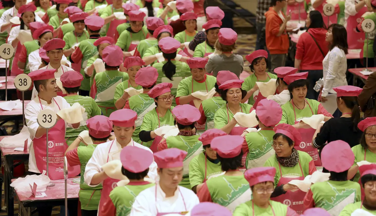 Ratusan orang memegang adonan pizza untuk pecahkan rekor Guinness World Record di Cina, Rabu (28/10/2015). Mereka berupaya untuk memecahkan rekor orang terbanyak melempar adonan pizza. (REUTERS/Stringer)