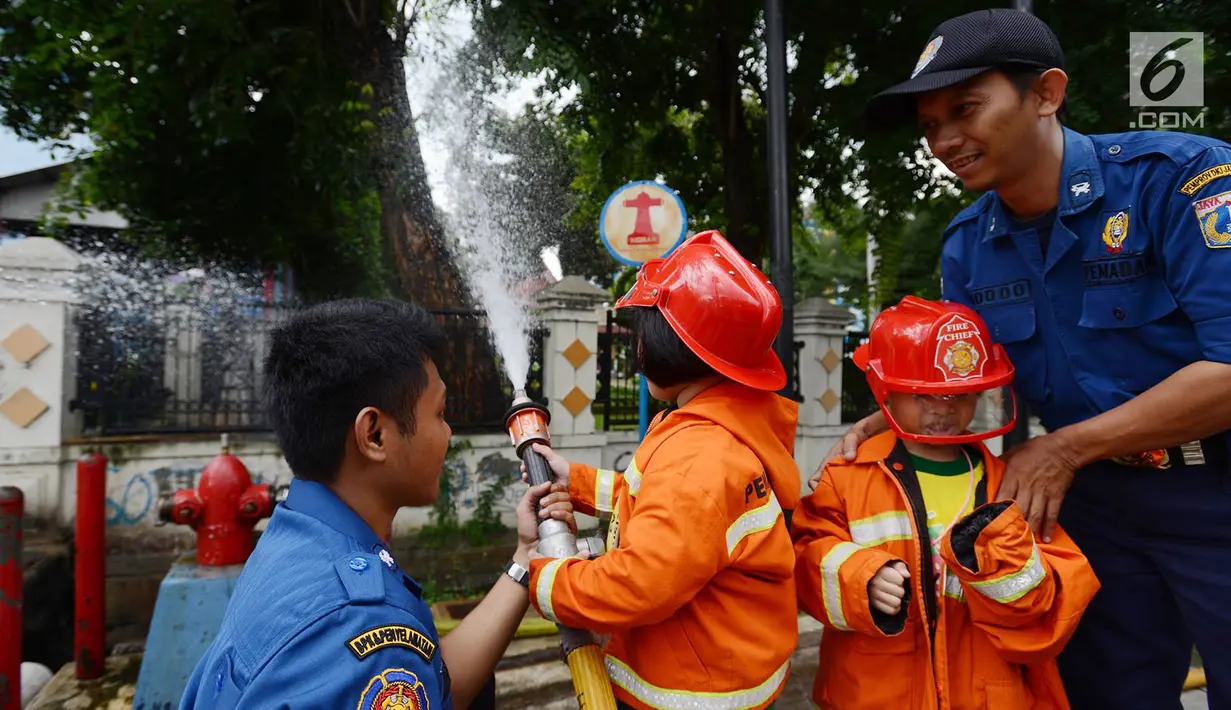 Petugas pemadam kebakaran mengajari anak-anak TK cara memadamkan api di Jakarta, Kamis (21/3). Kegiatan ini bertujuan mengenalkan profesi pemadam kebakaran dan memberi pengetahuan proses pemadaman api kepada anak usia dini. (merdeka.com/Imam Buhori)