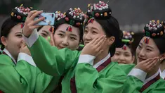 Pelajar berswafoto sambil mengenakan kostum tradisional Korea Selatan (Korsel) setelah upacara Coming of Age Day di Namsan Hanok Village, Seoul, Senin (15/5). Coming of age day atau Hari Kedewasaan dirayakan pada minggu ketiga bulan Mei. (Ed JONES/AFP)