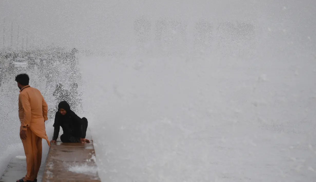 Seorang wanita menikmati percikan air ombak selama musim panas di laut Arab di Karachi, Pakistan (14/6/2019). Memasuki musim panas, warga Pakistan ramai-ramai mendinginkan tubuhnya di laut. (AFP Photo/Asif Hassan)