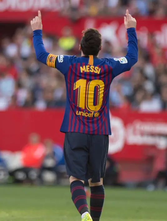 Penyerang Barcelona Lionel Messi menunjuk langit usai mencetak gol ke gawang Sevilla pada laga La Liga di Stadion Ramon Sanchez Pizjuan, Sevilla, Sabtu (23/2). Messi mencetak hattrick. (JORGE GUERRERO/AFP)