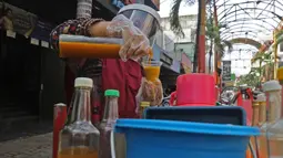 Tidar (46), melayani pembeli di Pasar Baru, Jakarta, Kamis (11/06/2020). Penjual jamu tradisional keliling ini tampak mematuhi protokol kesehatan pencegahan COVID-19 dengan mengenakan masker, face shield, dan sarung tangan dalam melayani pelanggan setianya. (Liputan6.com/Herman Zakharia)