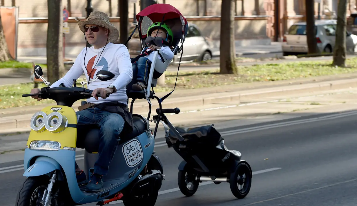Seorang pria bersama anaknya ikut serta dalam parade kendaraan listrik di Wina, Austria, 13 September 2020. Ratusan kendaraan listrik ambil bagian dalam parade E-Mobility "Rock the Ring" untuk mempromosikan mobilitas bebas emisi dan ramah iklim. (Xinhua/Guo Chen)