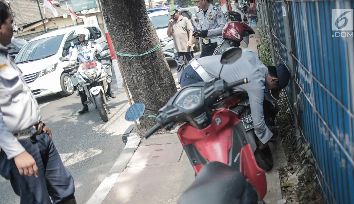 Petugas Dishub DKI Jakarta merazia  kendaraan roda dua dengan mencopot pentil yang terparkir di trotoar di kawasan Cipete Raya, Jakarta, Selasa (13/8/2019). Razia tersebut dilakukan Dishub untuk mengembalikan fungsi trotoar untuk pejalan kaki. (Liputan6.com/Faizal Fanani)