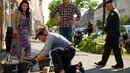 Aksi seniman Jerman, Gunter Demnig saat menempatkan monumen Stolpersteine (batu sandungan) di trotoar sebuah bangunan perumahan di Berlin (25/4/2014) mendapat perhatian dari warga setempat. (REUTERS/Thomas Peter)