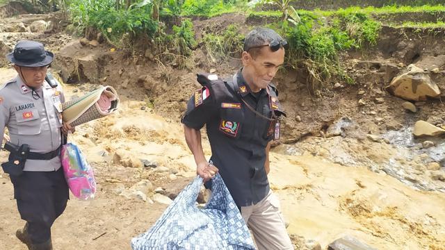 <span>Nampak dua anggota Kepolisian Resort Garut, tengah memberikan pertolongan membawa beberapa barang milik warga setelah musibah banjir bandang di wilayah Kecamatan Karangtengah. (Liputan6.com/Jayadi Supriadin)</span>
