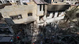 Orang-orang berkumpul di sekitar bangunan yang dirusak dan dibakar oleh pasukan Israel selama penggerebekan di kamp pengungsi Jenin Tepi Barat, pada 26 Januari 2023. Tentara Israel menggunakan gas air mata di dalam rumah sakit dan menolak berkomentar ketika ditanya oleh AFP tentang tuduhan gas air mata. (AFP/Jaafar Ashtiyeh)