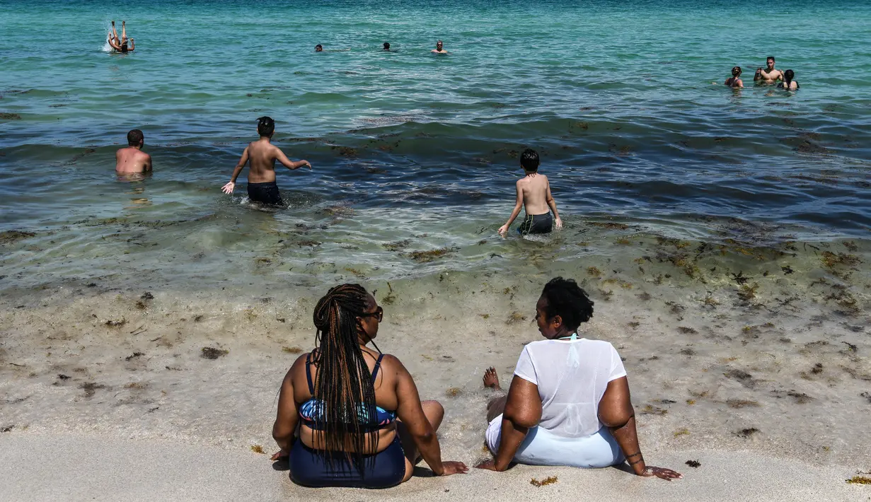 Orang-orang menikmati bermain air di Miami Beach, Florida, Rabu (10/6/2020). Pantai Miami dibuka hari ini untuk pertama kalinya setelah hampir tiga bulan ditutup guna menekan jumlah penyebaran corona Covid-19. (CHANDAN KHANNA / AFP)