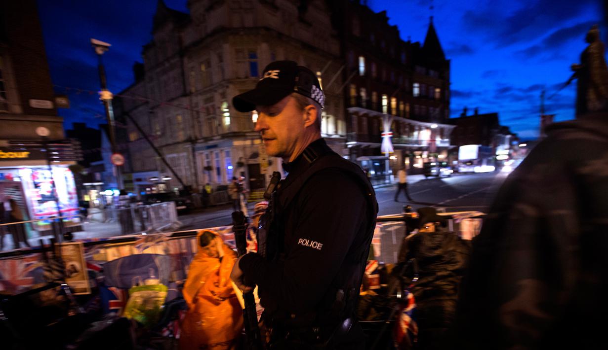 Petugas berjaga saat sejumlah penggemar Kerajaan Inggris duduk di luar Istana Windsor menjelang pernikahan Pangeran Harry dan Meghan Markle di Windsor, Inggris, (16/5). (AP Photo / Emilio Morenatti)