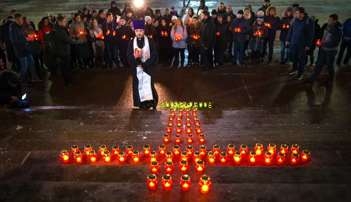 Warga dengan seorang imam berkumpul di Katedral Kristus Juruselamat Moskow, Rusia, Senin (12/2). Mereka menyalakan lilin untuk mengenang 71 korban tewas kecelakaan pesawat Rusia di Moskow. (AP Photo / Alexander Zemlianichenko)
