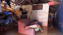 Seorang warga beristirahat di sofa di rumahnya yang terendam banjir di desa Sukajaya di Serang (1/3/2022).  Banjir merendam Kota Serang akibat hujan deras yang turun sejak Senin malam (28/2/2022) hingga hari ini. (AFP/Dziki Oktomauliyadi)