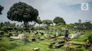 Petugas membersihkan makam yang ada di TPU Karet Bivak, Jakarta, Kamis (4/3/2021). Komisi D DPRD DKI Jakarta meminta kepada Pemprov DKI Jakarta khusunya Dinas Pertamanan dan Hutan Kota untuk menyederhanakan proses izin perpanjangan sewa makam di Jakarta. (Liputan6.com/Faizal Fanani)