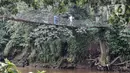 Anak-anak melintasi jembatan gantung yang sudah tidak layak di kawasan Srengseng Sawah, Jakarta, Sabtu (12/6/2021). Kondisi jembatan gantung yang menjadi akses warga dari Cimanggis menuju Srengseng Sawah atau sebaliknya tersebut beralaskan bambu serta seng. (merdeka.com/Iqbal S. Nugroho)