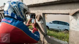 Seorang warga mengambil gambar mobil yang terperosok di saluran Ispeksi Kalimalang, Jabar, Minggu (7/5). Penyebab kecelakaan itu diduga pengemudi mengantuk dan menghindari pengendara motor sehingga tercebur kedalam Kalimalang.(Liputan6.com/Gempur M Surya)