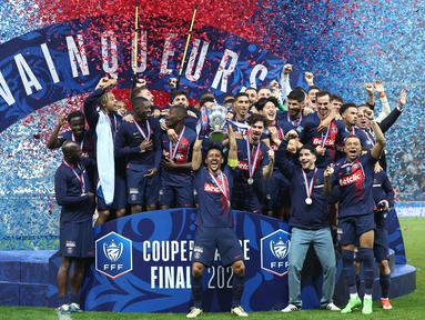 Bek Paris Saint-Germain #05 Marquinhos (tengah) mengangkat trofi Coupe de France 2023/2024 saat berselebrasi dengan timnya setelah menang atas Olympique Lyon pada laga final di Stadion Pierre-Mauroy, Minggu (26/5/2024) dini hari WIB. (FRANCK FIFE / AFP)