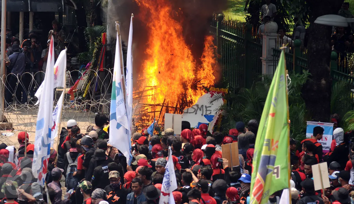 Sebuah karangan bunga dibakar massa saat aksi perayaan MayDay di Jalan Medan Merdeka Barat, Senin (5/1). Ribuan massa buruh turun ke jalan dalam perayaan Hari Buruh Internasional. (Liputan6.com/Helmi Fithriansyah)