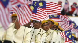 Warga mengikuti parade kemerdekaan sambil mengibarkan bendera Malaysia saat perayaan Hari Kemerdekaan ke-58 di Kuala Lumpur, Senin (31/8/2015).  Perayaan kemerdekaan kali ini dilakukan di tengah desakan mundur kepada PM Najib. (REUTERS/Olivia Harris)