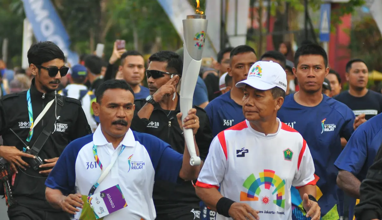 Petinju legendaris Indonesia, Nico Thomas, membawa obor Asian Games XVIII saat melintasi di Kota Malang, Jawa Timur, Jumat (20/7/2018). Sebanyak 10 kota di Indonesia akan dilalui oleh obor Asian Games. (Bola.com/Iwan Setiawan)