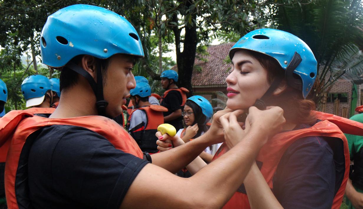 Krisshatta Luis Aveiro (kiri) dan Hilda Vitria Khan, memakai helm sebagai salah satu perlengkapan arung jeram sebelum berpetualang di Sungai Cicatih, Sukabumi, Sabtu (12/12/2015). (Bola.com/Arief Bagus)