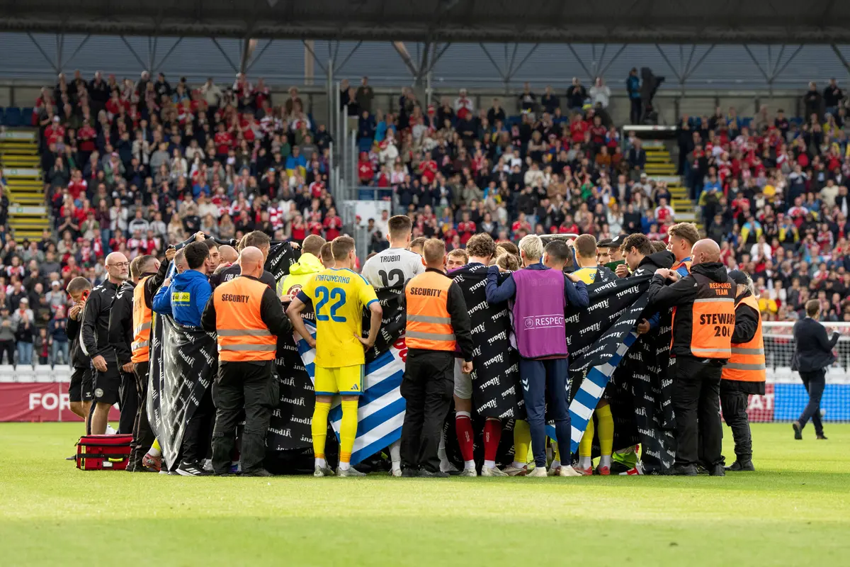 Pemain Timnas Denmark dan Timnas Ukraina membentuk lingkaran di sekitar Christian Eriksen yang jatuh pingsan di tengah pertandingan di Odensen, Denmark, Minggu (07/06/2026) malam WIB.