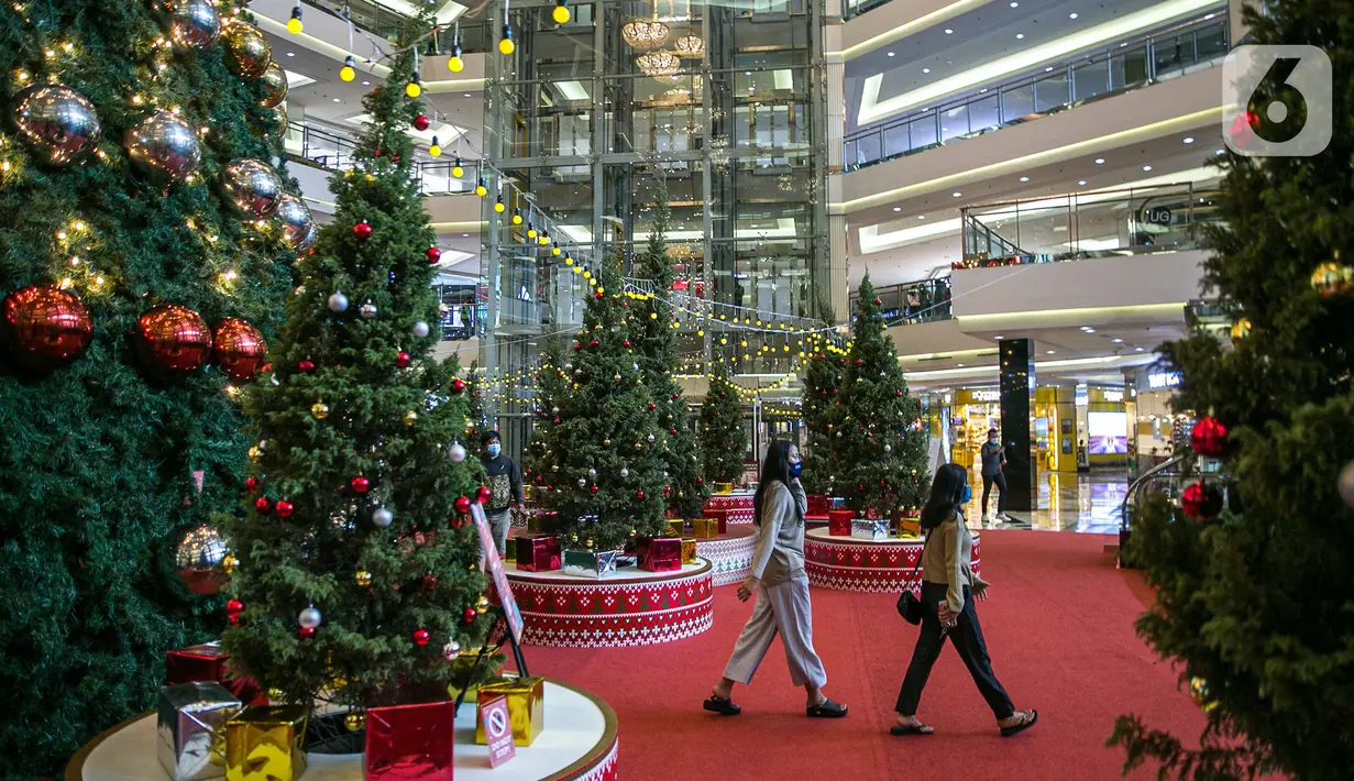 Pengunjung melintas di dekat Pohon Natal Raksasa  di Mall Taman Anggrek, Jakarta, Senin (21/12/2020). Mal ini juga memasang pohon Natal megah dikelilingi beberapa pohon cemara asli dihiasi bola-bola kecil berwarna merah dan silver. (Liputan6.com/Faizal Fanani)