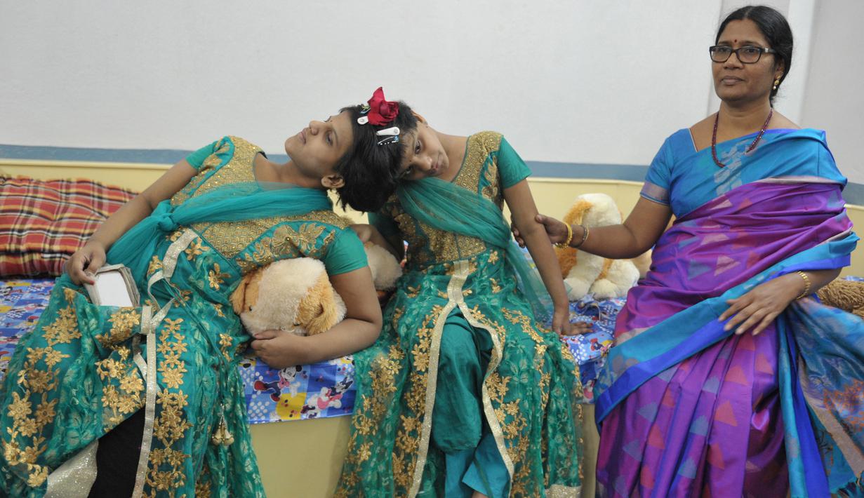 Anak kembar siam, Veena (kanan) dan Vani yang berusia 14 tahun didampingi Direktur Joint Regional untuk Pembangunan Perempuan dan Kesejahteraan Anak, D. Lalitha Kumari di Rumah Anak di Hyderabad, India (2/1). (AFP/Noah Seelam)