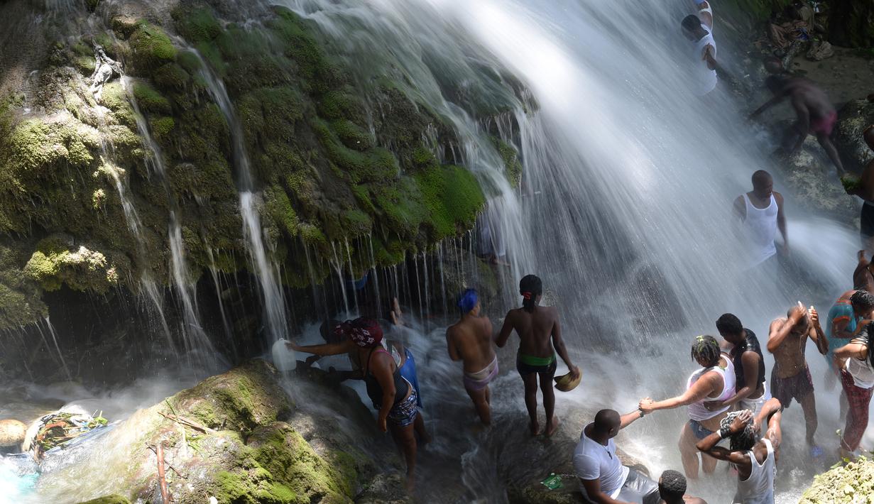 Sejumlah peziarah mandi di bawah air terjun di Saut d' Eau, Haiti (15/7). Ini merupakan ritual tahunan untuk menyembuhkan penyakit dan mensucikan diri. (AFP Photo/Hektor Retamal)