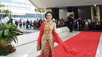 Krisdayanti tampil mengenakan kebaya panjang brokat warna emas dari Anne Avantie dipadukan bawahan kain songket Palembang warna merah. [Instagram/@krisdayantilemos]