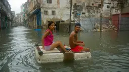 Sepasang warga menggunakan styrofoam untuk melewati jalanan yang terendam banjir di Hanava, Kuba, Minggu (10/9). Badai irma yang melanda pantai timur Perairan Kuba pada Jumat waktu setempat menyebabkan sebagian kota terendam banjir. (AP/Ramon Espinosa)