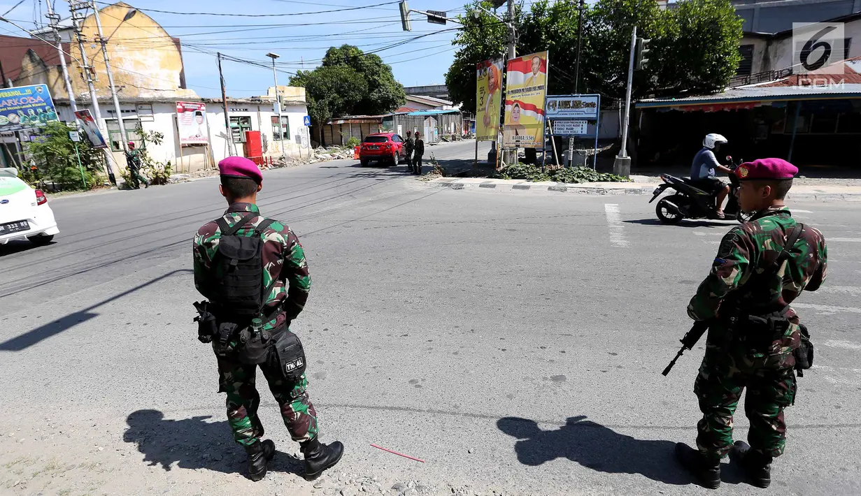 Dua prajurit Marinir TNI Angkatan Laut berjaga di perempatan lampu merah kota Palu pascagempa dan tsunami di Palu, Sulawesi Tengah, Jumat (5/10). Selain berjaga di jalan, mereka juga berjaga di beberapa ruko di Palu. (Liputan6.com/Fery Pradolo)