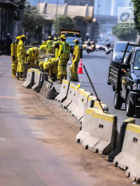 Petugas Dinas Bina Marga DKI Jakarta memperbaiki separator busway di kawasan Jalan Gatot Subroto, Jakarta, Selasa (1/10/2019). Separator busway dirusak massa saat terjadi bentrok antara polisi dengan demonstran di kawasan tersebut. (Liputan6.com/Faizal Fanani)