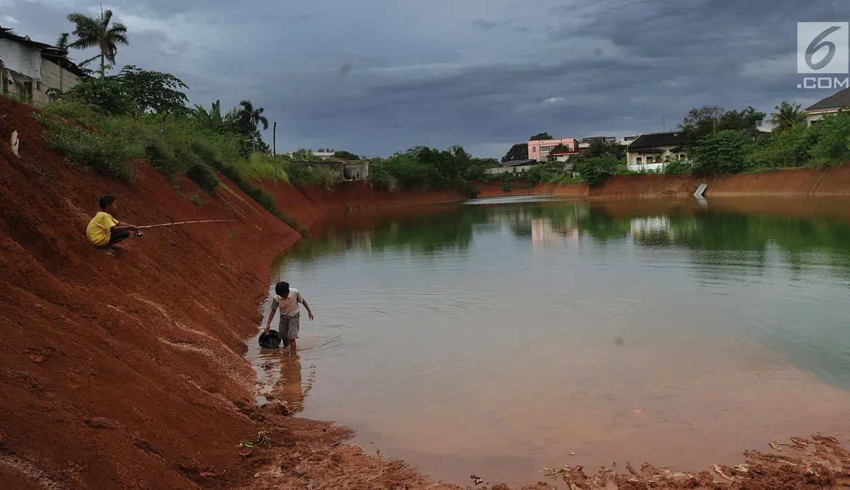 Anak-anak memancing pada bagian proyek pembangunan tol Cinere-Serpong yang berubah menjadi danau sedalam 4 meter di kawasan Cipayung, Tangsel, Banten (17/1). Pembangunan jalan Tol ini sepanjang 10,14 kilometer. (Merdeka.com/Arie Basuki)