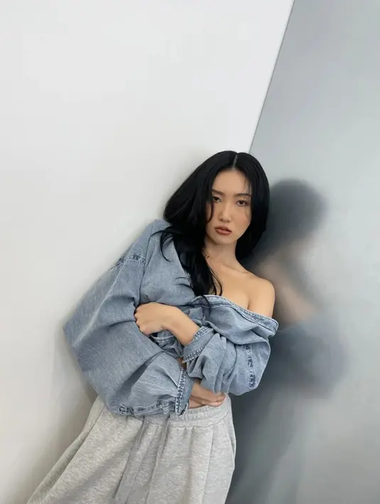 Gaya berani Hwasa tak hanya seputar pilihan outfit tapi juga styling. Ia gunakan kemeja denim oversized bergaya sabrina dan sweatpants [@_mariahwasa]