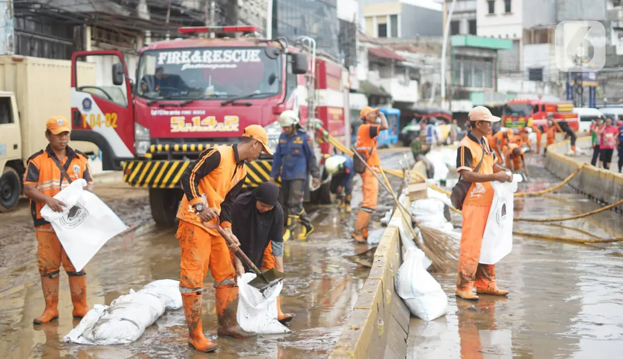 Petugas Penanganan Prasaran dan Sarana Umum (PPSU) membersihkan lumpur yang mengendap di sepanjang Jalan Jatinegara Barat, Kampung Melayu, Jakarta Timur, Kamis (2/1/2020). Petugas melakukan bersih-bersih menyusul mulai surutnya banjir di kawasan tersebut. (Liputan6.com/Immanuel Antonius)