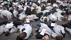 Petugas medis dari segala bidang menggelar aksi protes dengan merebahkan badan mereka dijalanan atau disebut gerakan "die-in" di New York, (29/10/2015). Hal ini menyinggung perihal perang di Suriah yang menewakan 700 petugas medis. (REUTERS/Carlo Allegri)