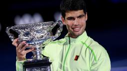 Carlos Alcaraz memamerkan piala usai berhasil menjuarai Australian Open 2026 setelah menaklukkan Novak Djokovic dalam laga sengit yang dilangsungkan di Melbourne Park pada (1/2/2026) sore WIB. (AFP/Izhan Khan)